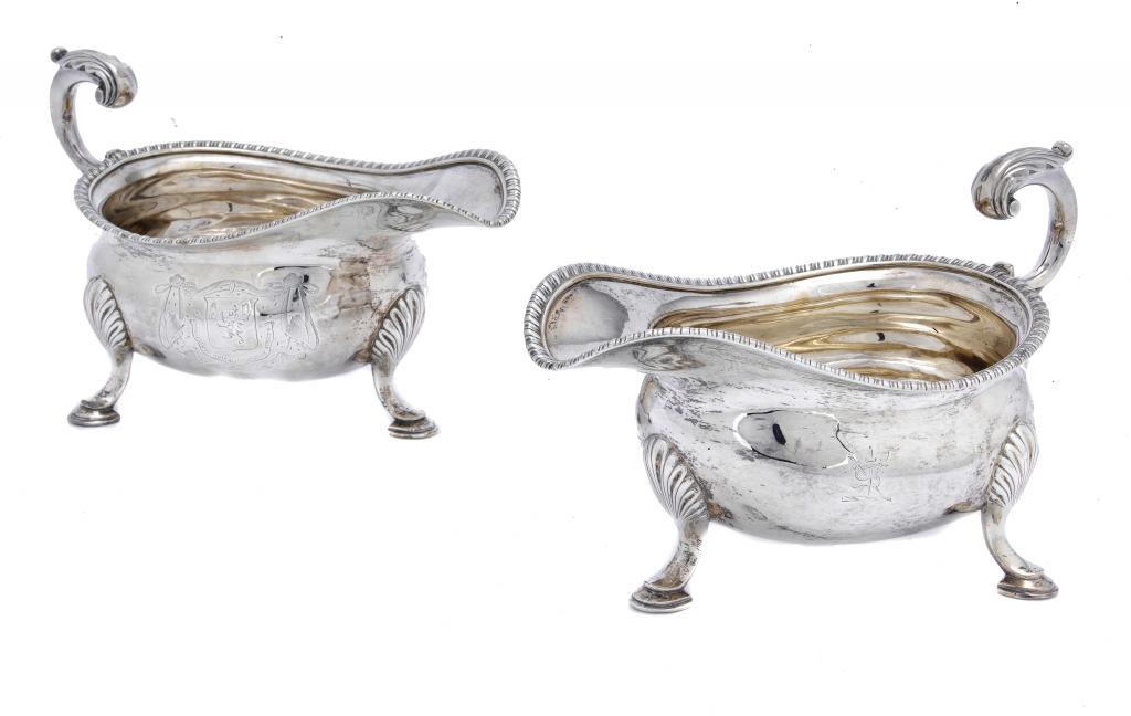 Appraisal: A PAIR OF GEORGE III SAUCE BOATS with leaf capped