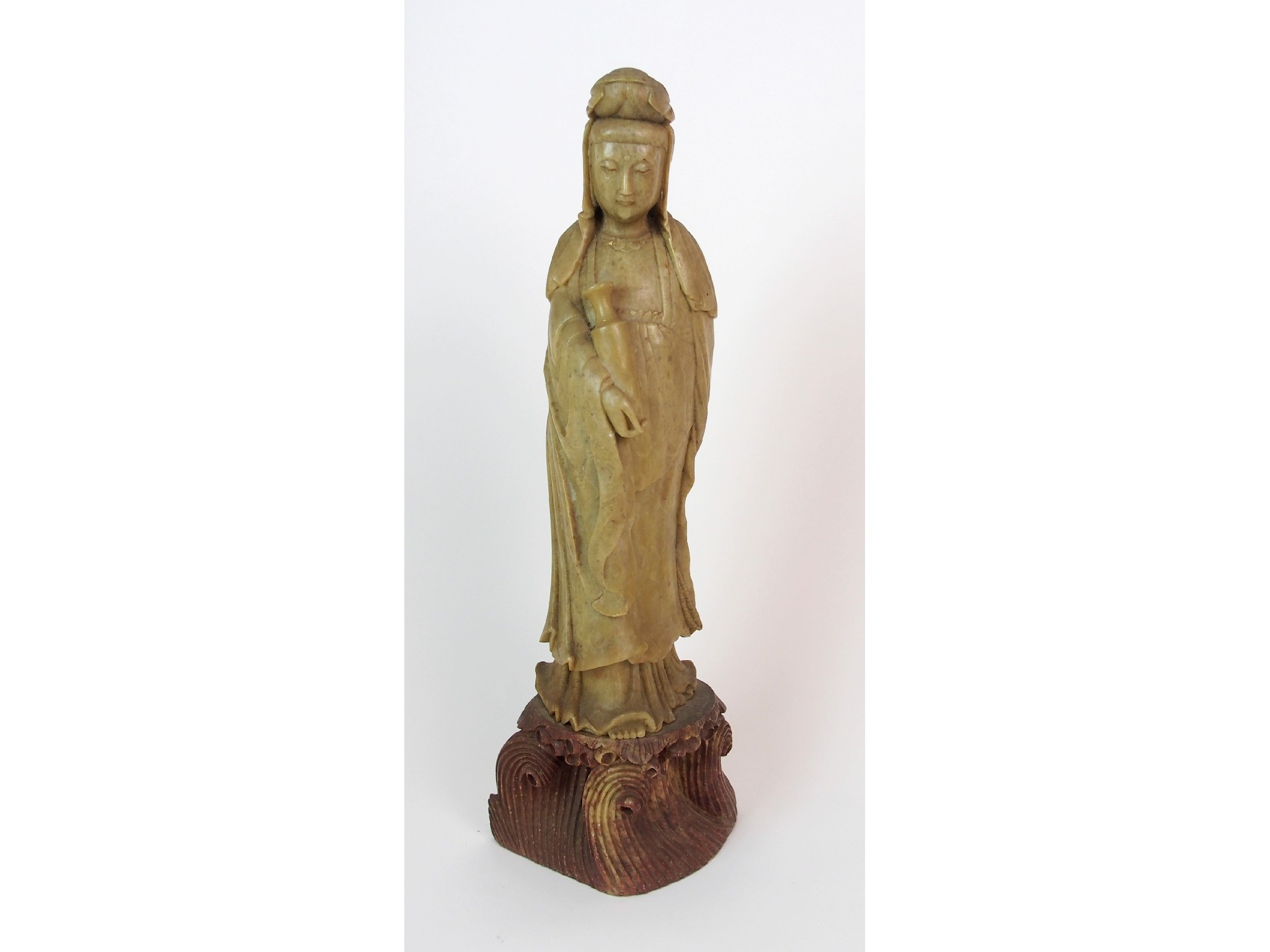 Appraisal: A Chinese soapstone carving of Guanyinstanding with a vase clasped