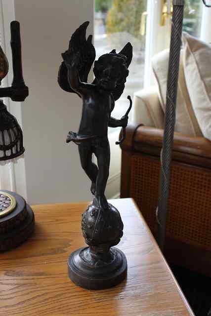 Appraisal: A BRONZE SCULPTURE OF CUPID standing on a celestial globe