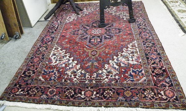 Appraisal: PERSIAN HERIZ CARPET centering a blue cruciform medallion on floral