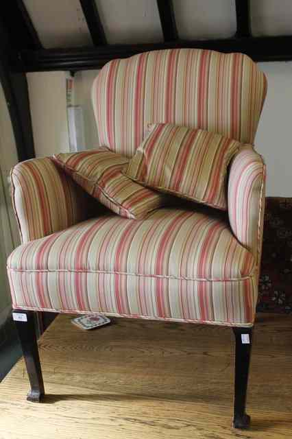 Appraisal: AN EDWARDIAN STRIPED UPHOLSTERED FIRESIDE CHAIR on mahogany tapering supports