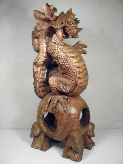 Appraisal: Bali carved wood dragon standing on ball in ball stand