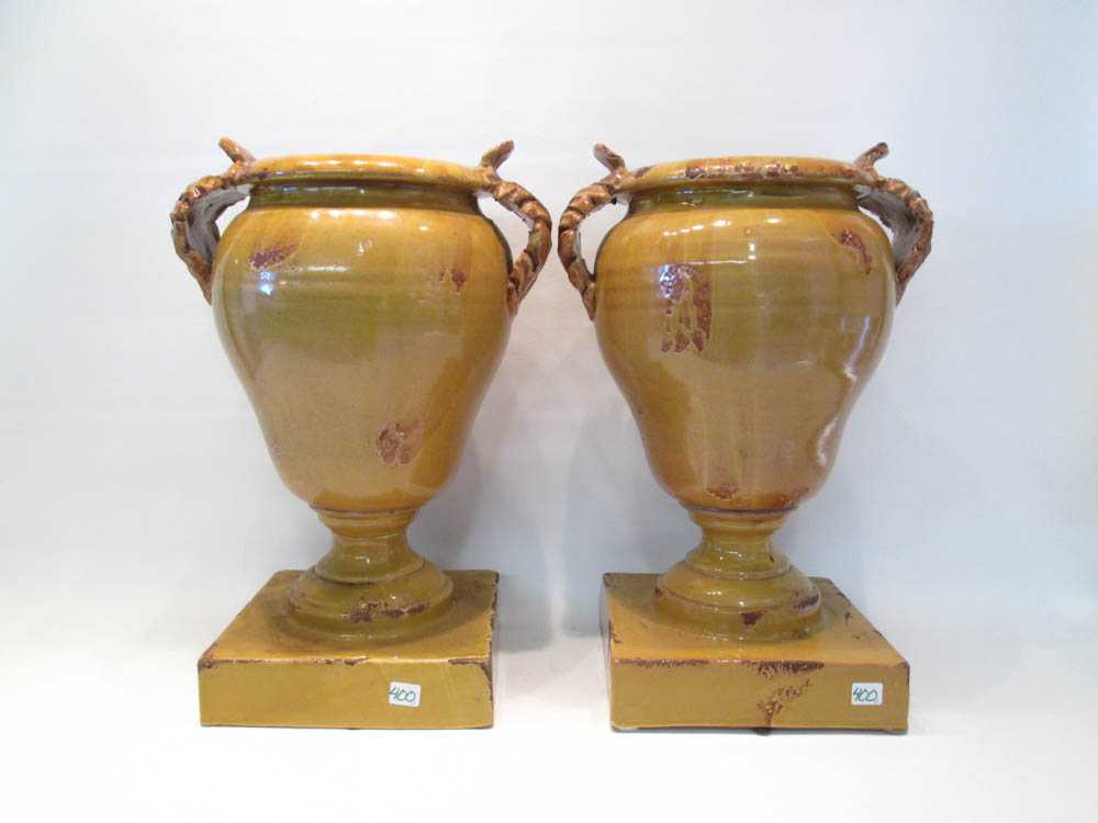 Appraisal: TWO FORTUNATA YELLOW GLAZED POTTERY URNS with applied split-handles artist