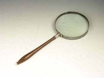 Appraisal: A large magnifying glass with a turned mahogany handle in