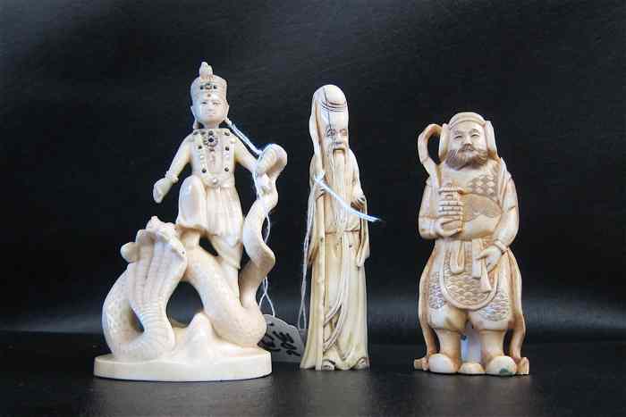 Appraisal: THREE IVORY CARVED CHINESE FIGURES man standing with stylized serpent