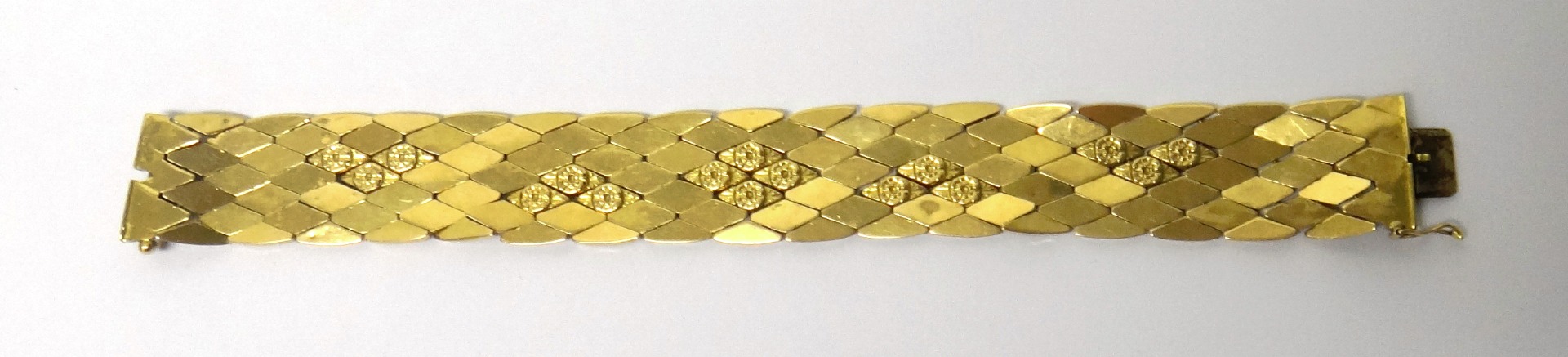 Appraisal: A gold bracelet in a wide lozenge shaped linkage design