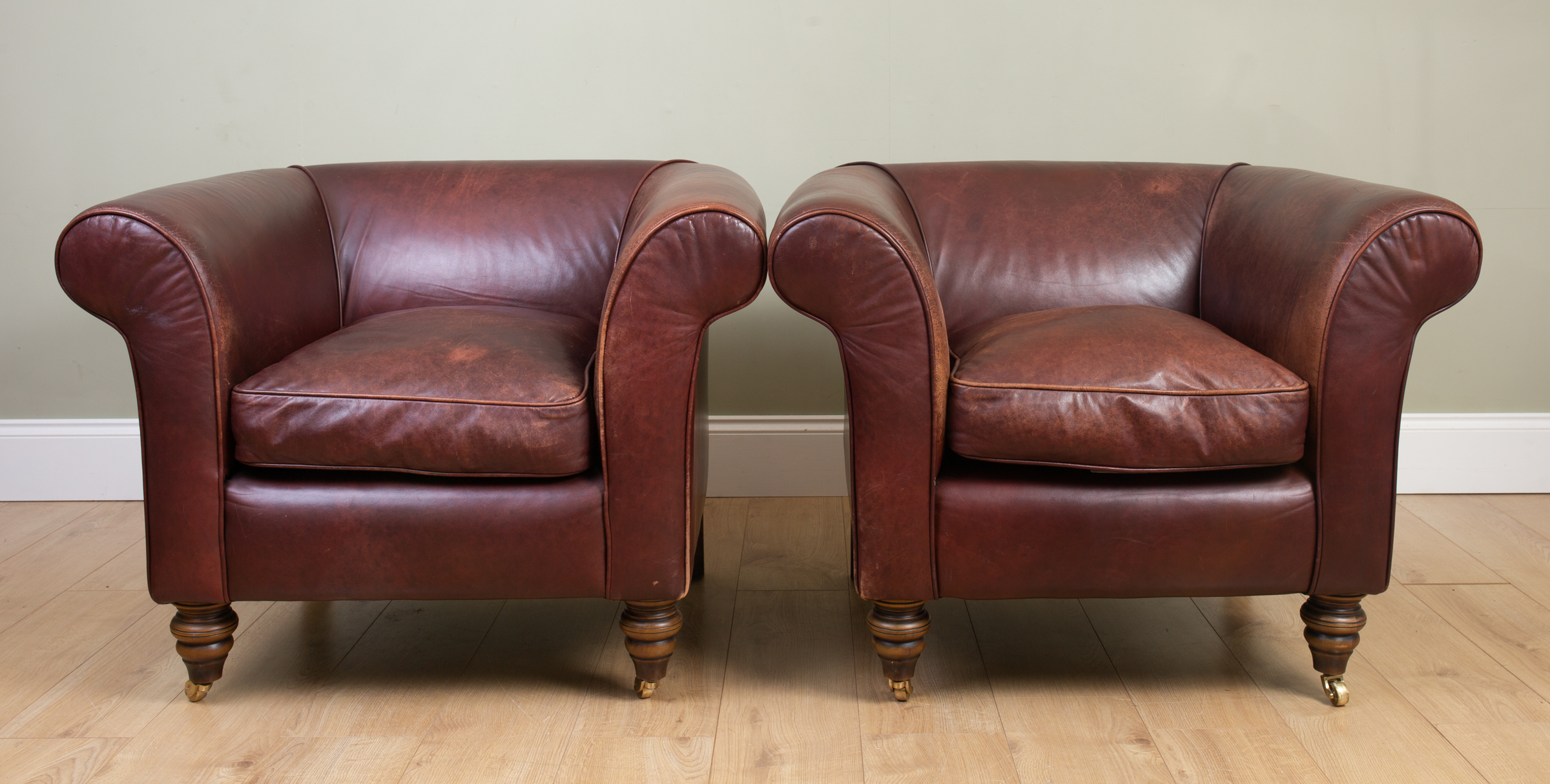 Appraisal: A pair of leather upholstered armchairs with scrolling arm and