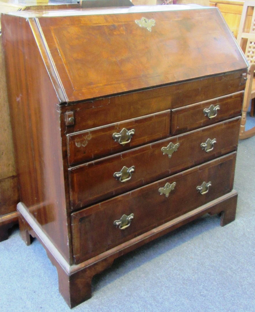 Appraisal: An th century feather banded walnut bureau with welled interior