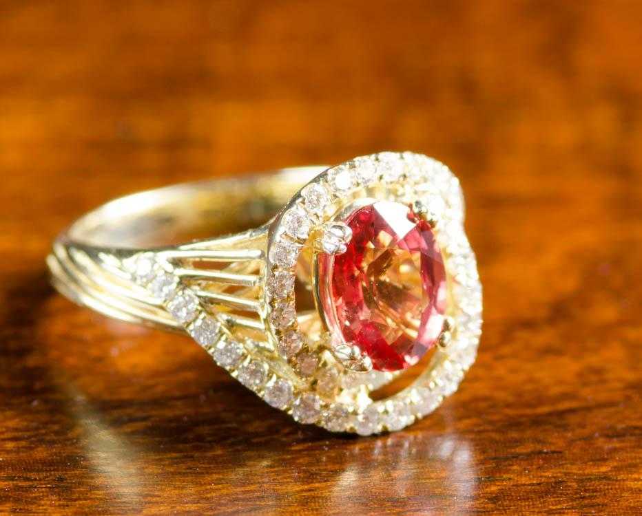 Appraisal: ORANGE SAPPHIRE AND FOURTEEN KARAT GOLD RING with round-cut diamonds