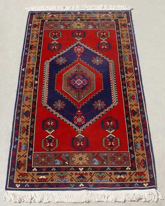 Appraisal: HAND TIED RUG Bright red ground with blue medallion Approx