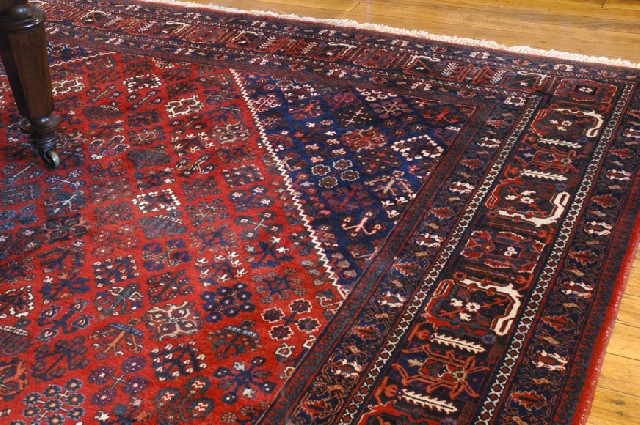 Appraisal: A PERSIAN CARPET Having a red ground and navy border