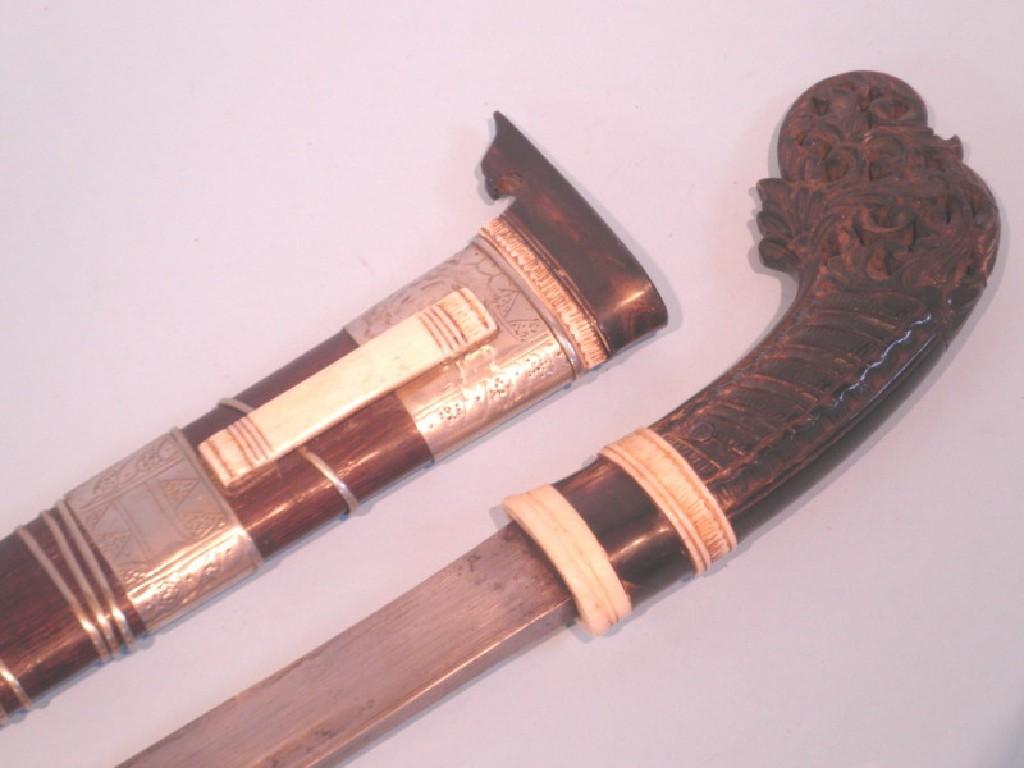 Appraisal: A Malayan short sword with white metal mounts and carved