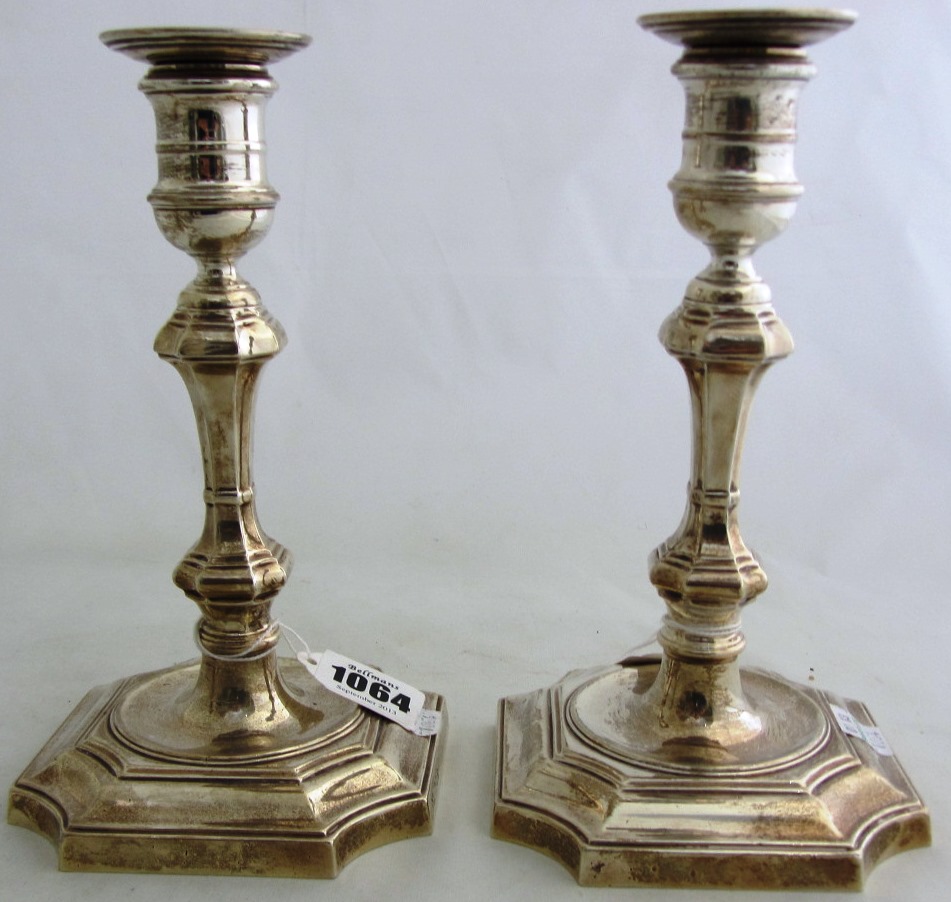 Appraisal: A pair of silver table candlesticks on shaped square loaded