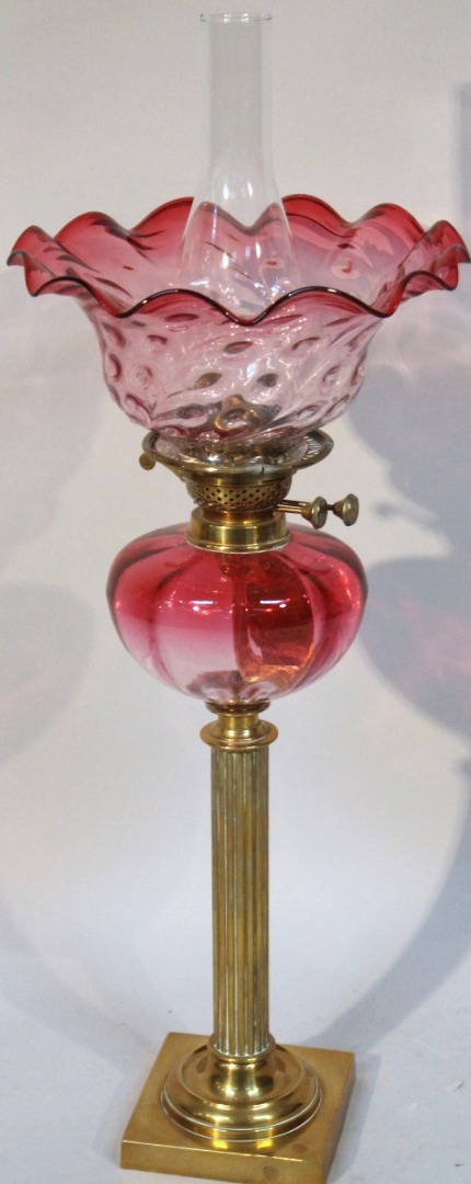 Appraisal: An Edwardian cranberry glass and brass oil lamp with a