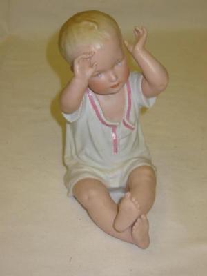 Appraisal: A HEUBACH PORCELAIN PIANO BABY modelled seated with raised arms