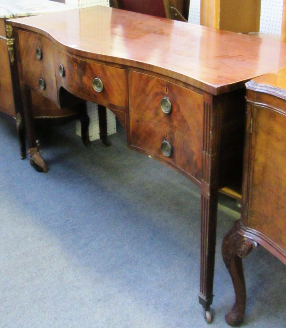 Appraisal: A George III serpentine mahogany sideboard with three frieze drawers