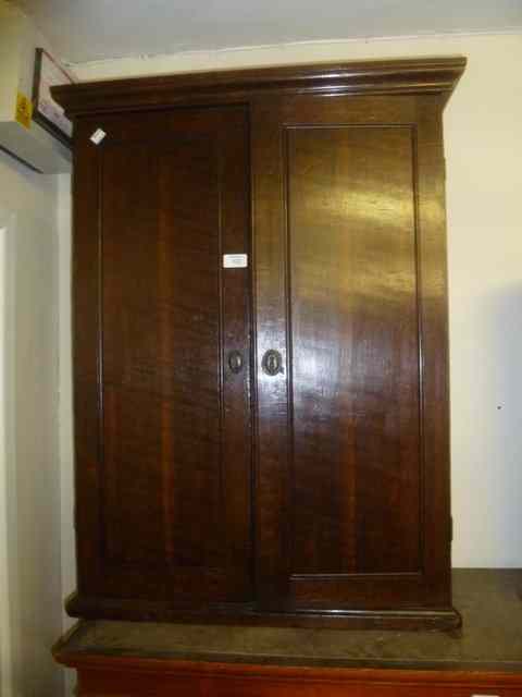 Appraisal: A GEORGIAN OAK WALL CUPBOARD enclosed by two panel doors