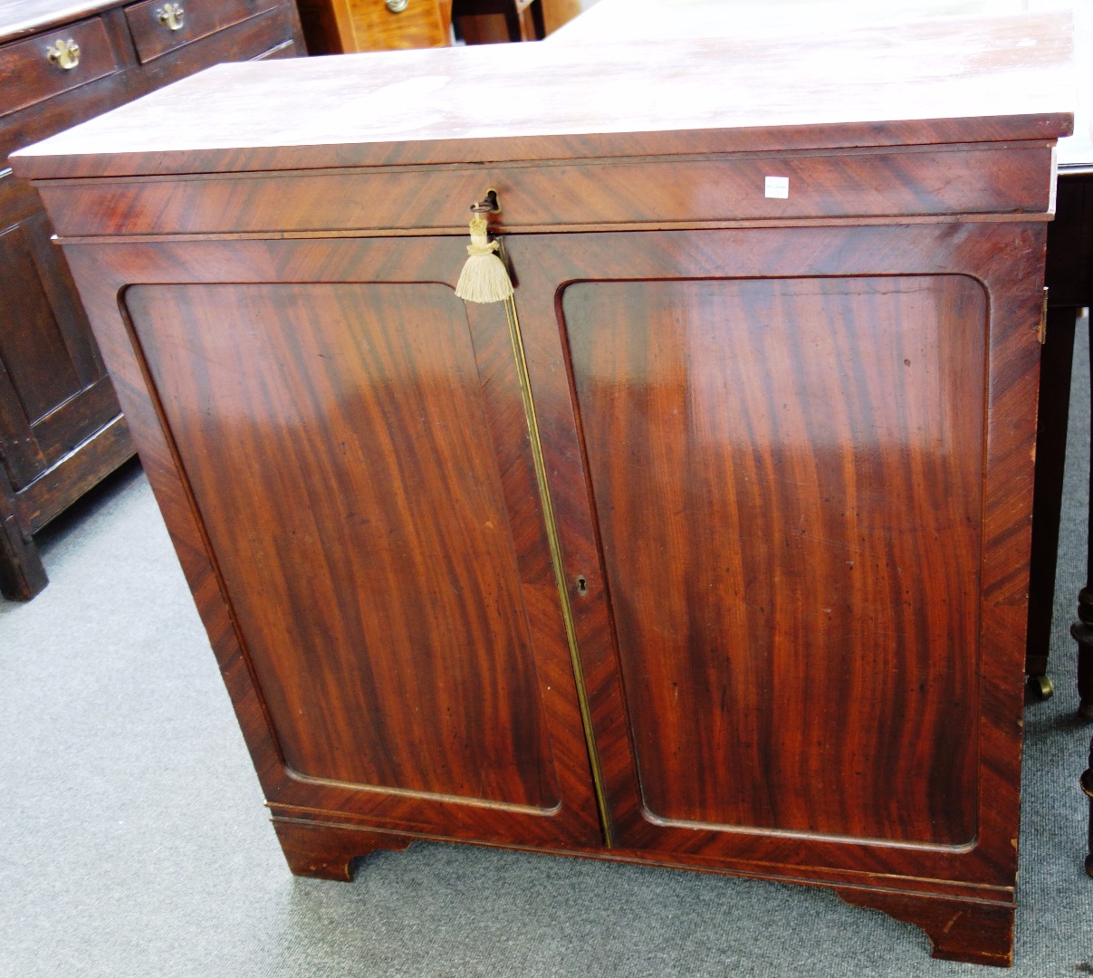 Appraisal: A th century mahogany side cupboard with lockable lift top