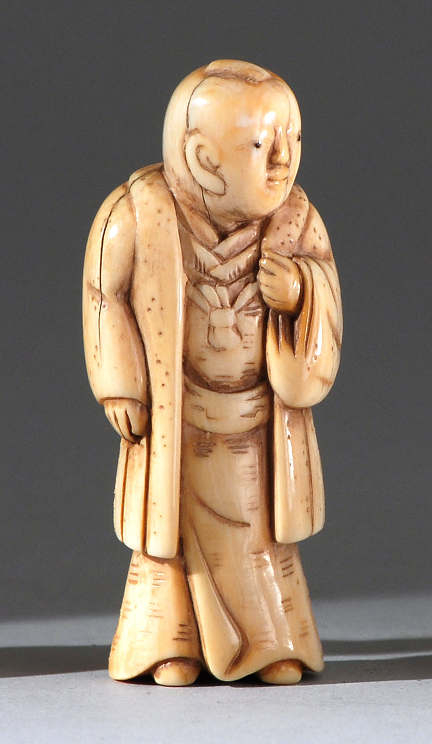 Appraisal: IVORY NETSUKE th th CenturyDepicting a standing nobleman with pensive