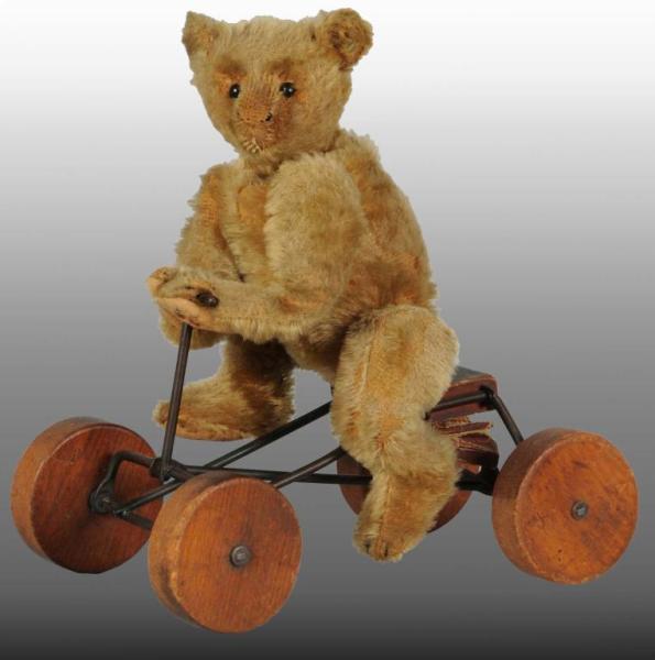 Appraisal: Early Steiff Teddy Bear on Toy Bicycle Description Wooden wheels