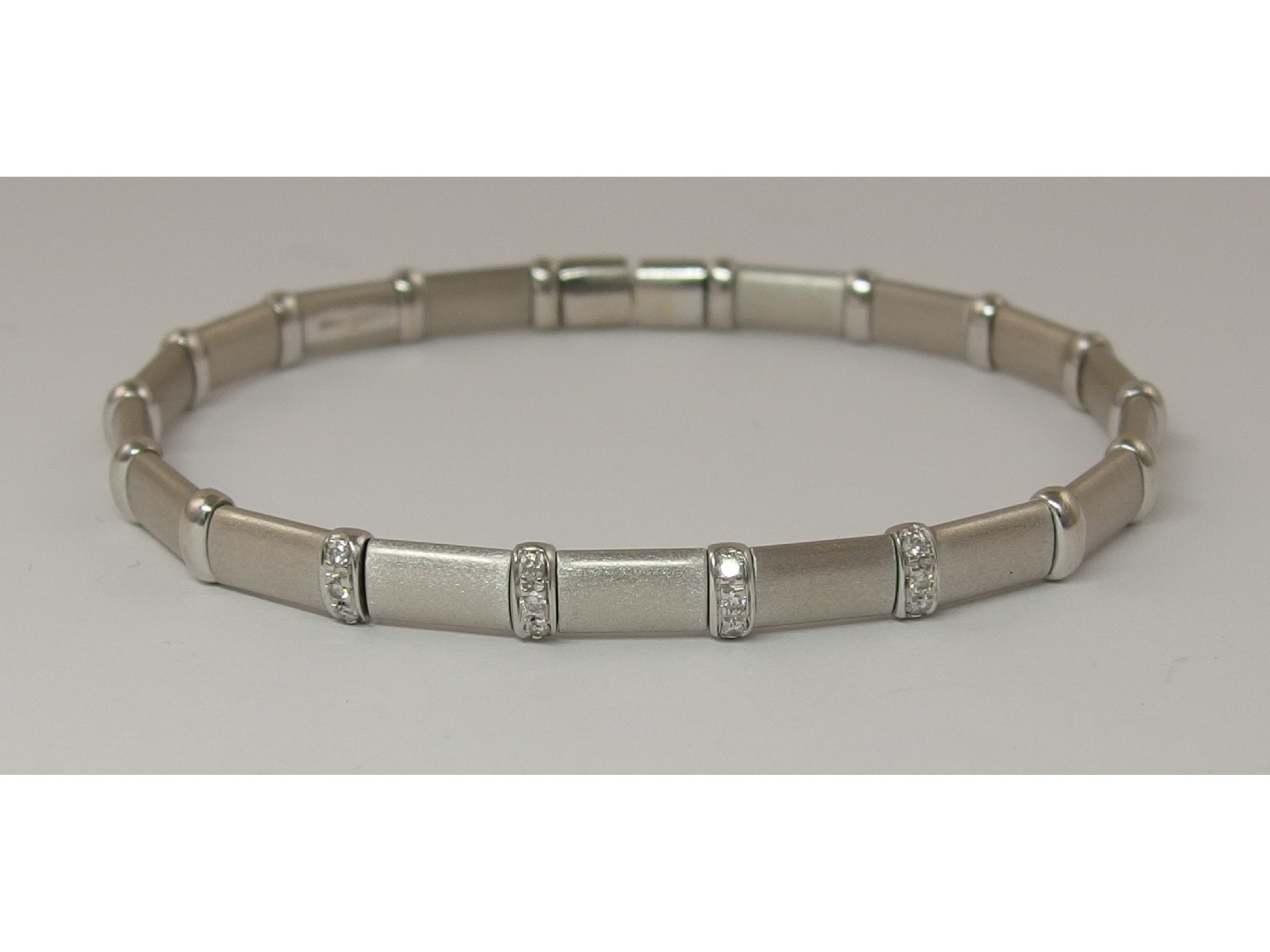 Appraisal: An Italian ct white gold sprung banglematt textured links interspaced