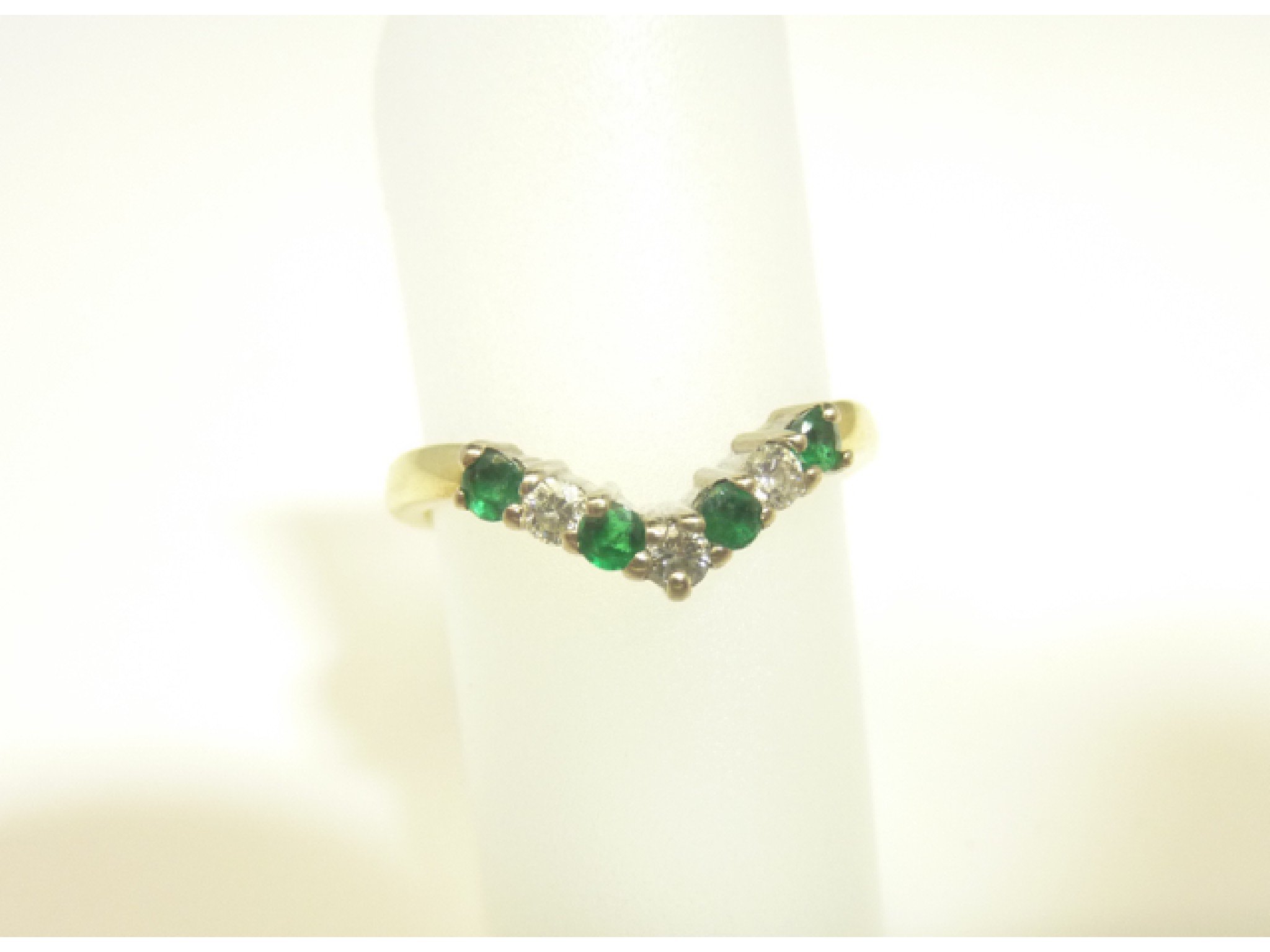 Appraisal: An emerald and diamond wishbone ring set with three round