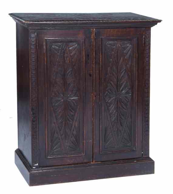 Appraisal: AN EDWARDIAN DARK CARVED OAK CUPBOARD with twin panelled doors