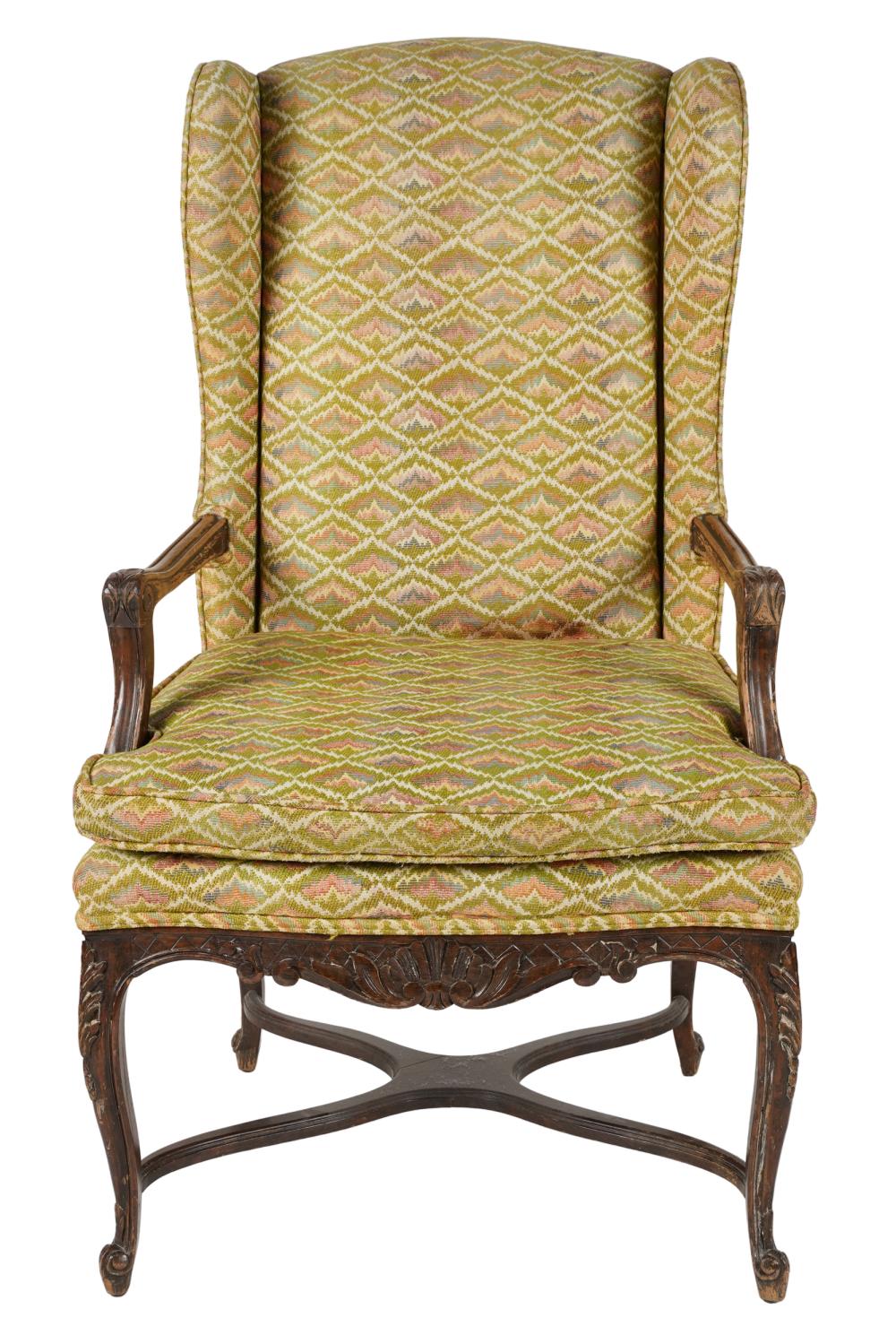 Appraisal: PROVINCIAL STYLE CARVED WOOD WINGBACK CHAIRcovered with green pink and