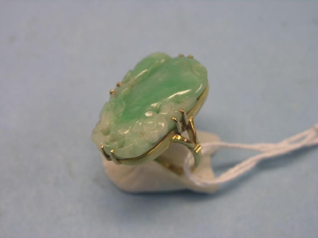 Appraisal: A gold and green jade ring carved detail claw-setting ring