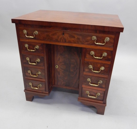 Appraisal: A figured mahogany and kneehole desk with a frieze drawer