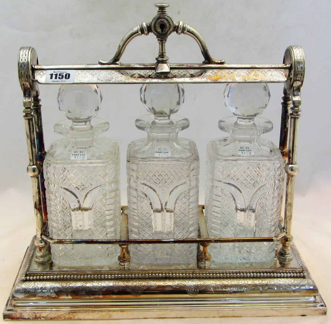 Appraisal: A silver plated tantalus fitted with three faceted glass decanters