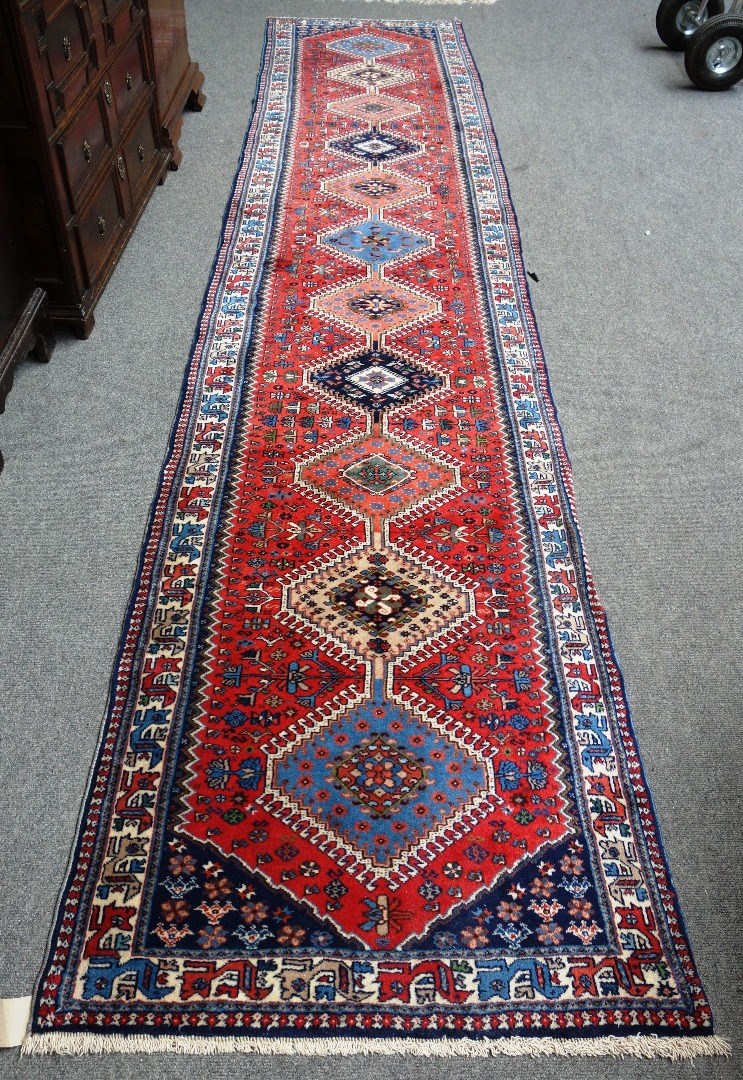 Appraisal: A modern red ground runner Heriz design with multiple hooked