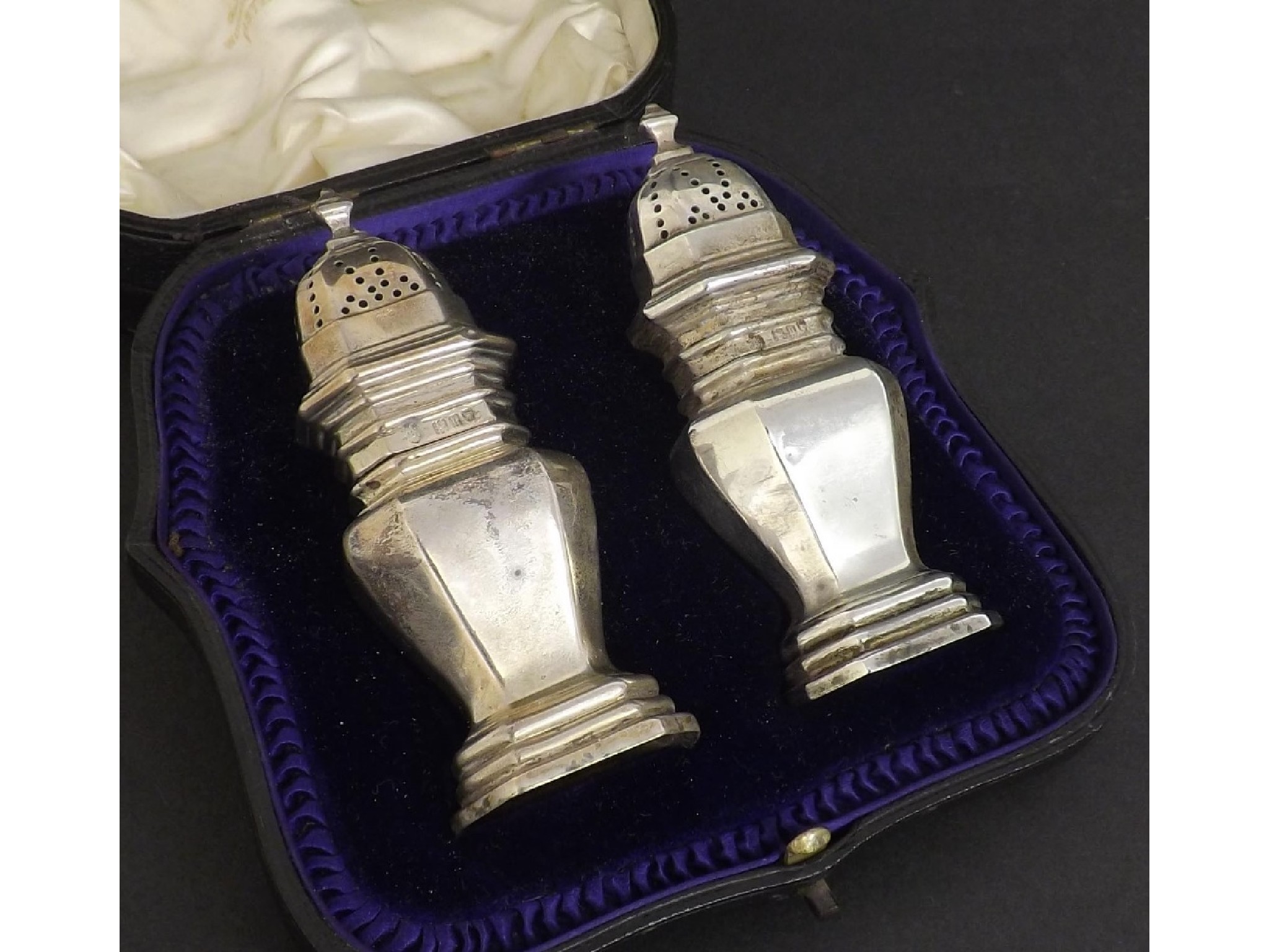 Appraisal: Pair of Edwardian silver faceted baluster peppers within a leather