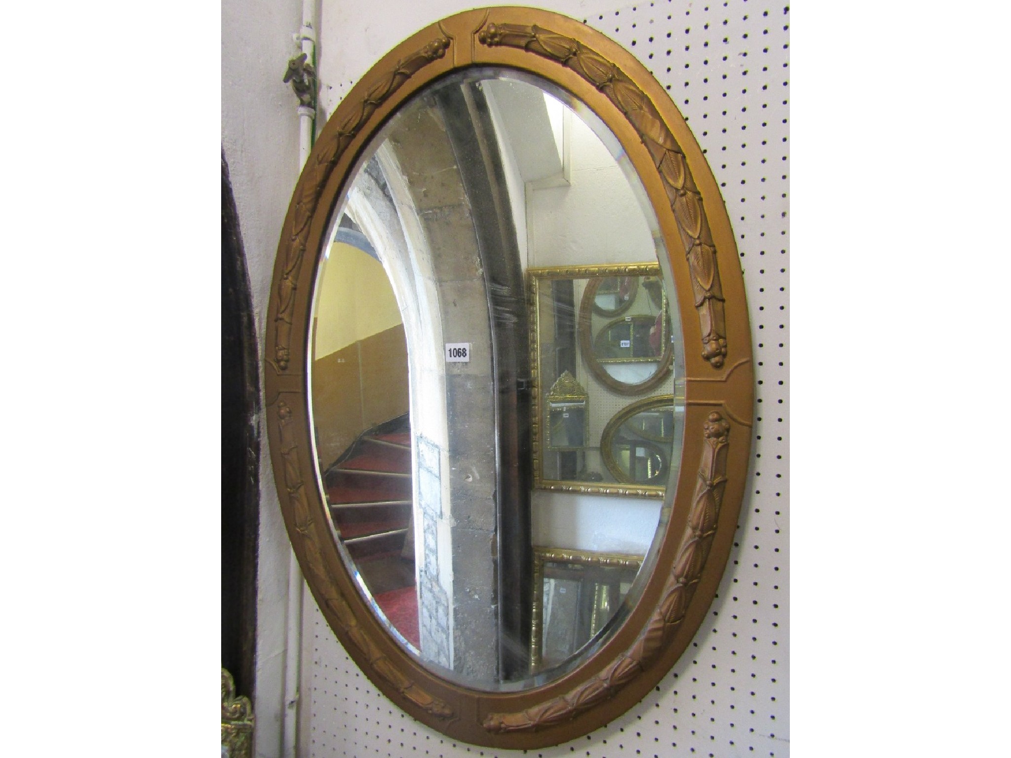 Appraisal: An oval painted metal clad wall mirror with bevelled edge