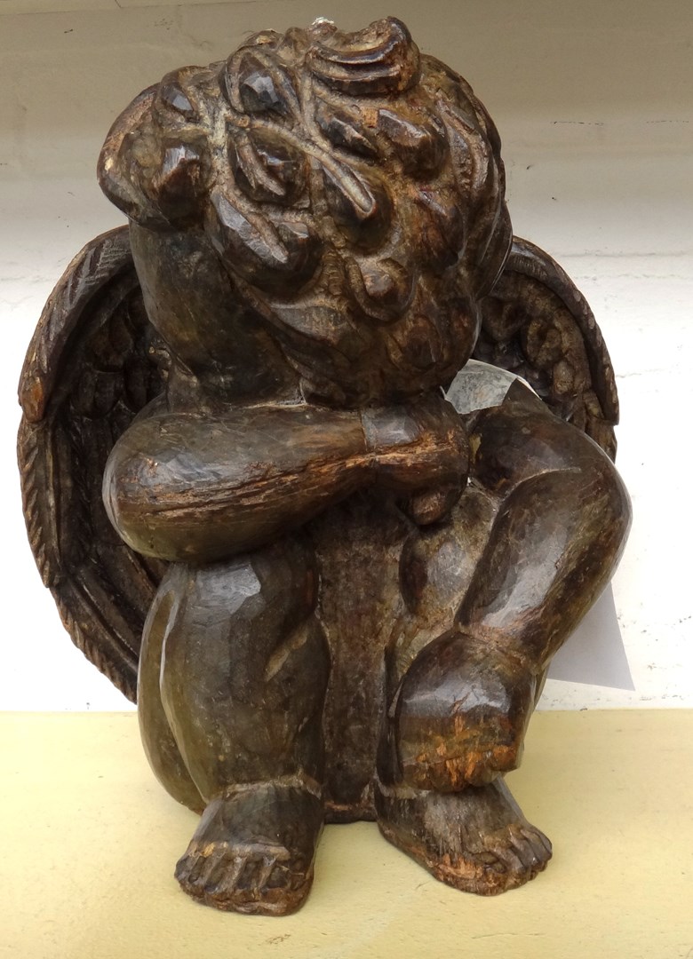 Appraisal: A modern carved hardwood figure of a seated putto cm