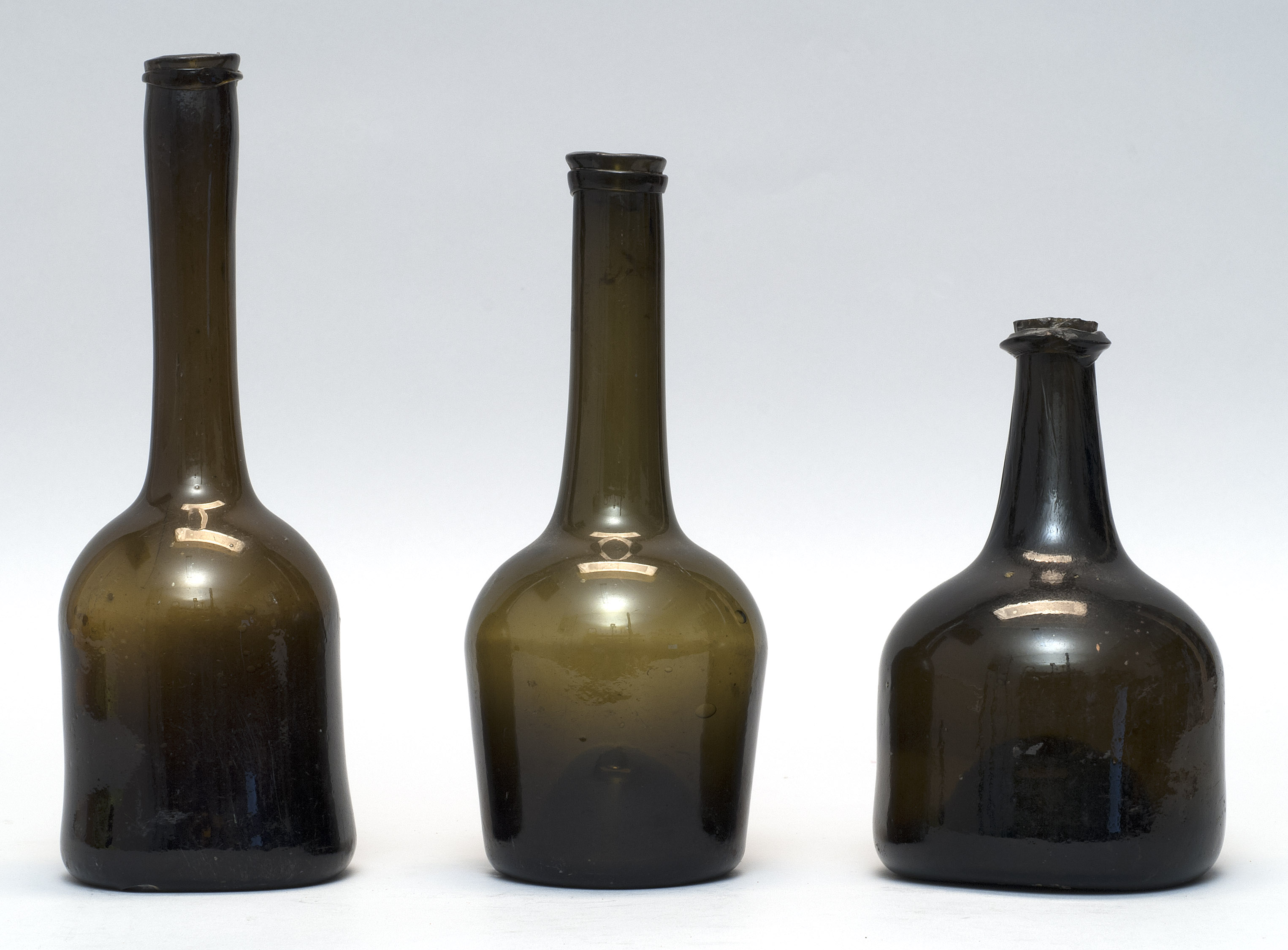 Appraisal: THREE FREE-BLOWN GLASS LIQUOR BOTTLES Continental th CenturyIn olive green