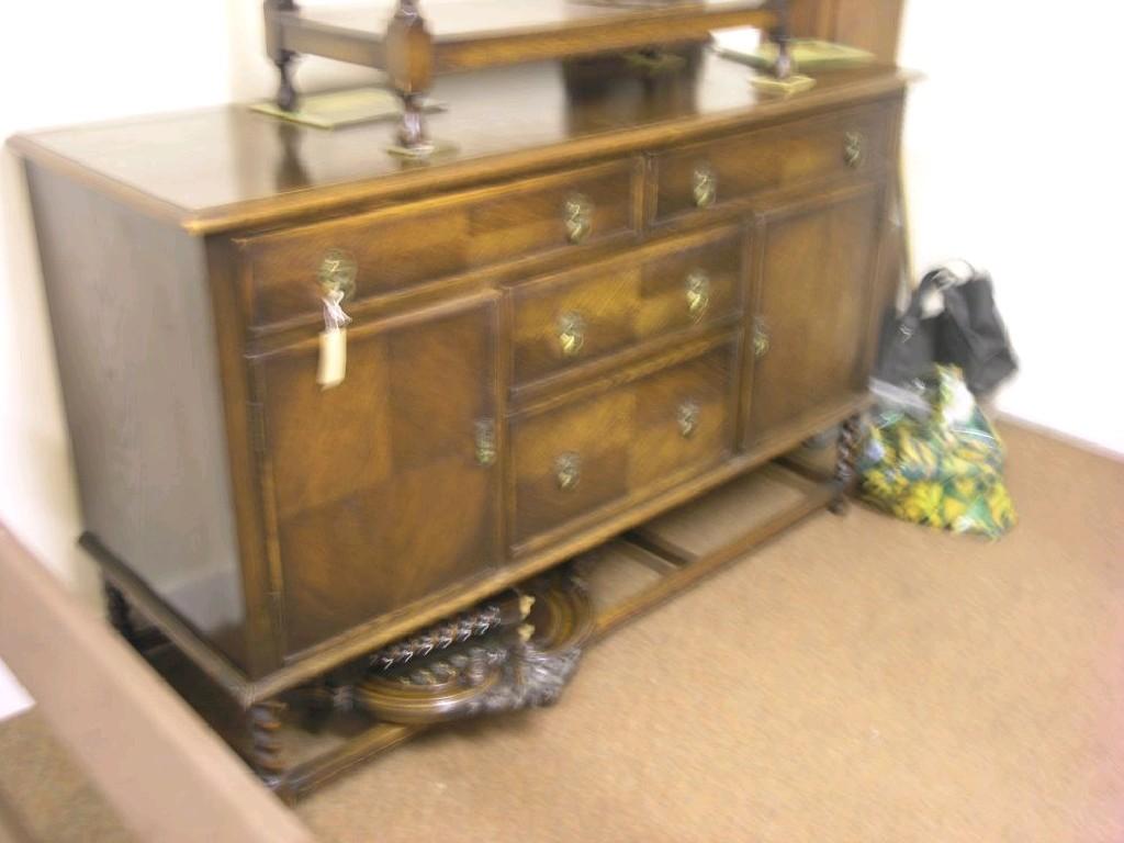 Appraisal: A dark oak sideboard caned and mirrored back above an