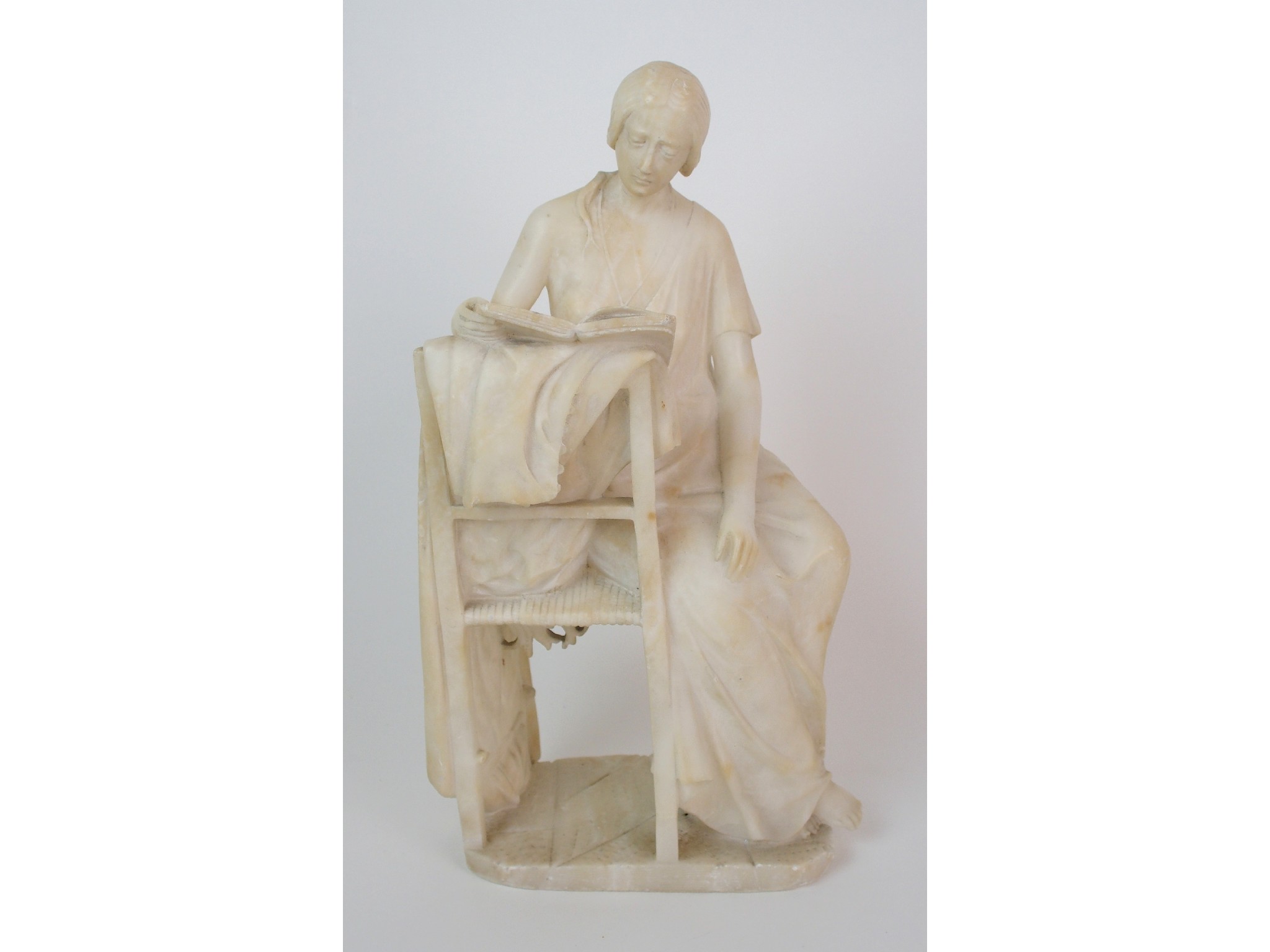 Appraisal: A Continental carved alabaster figuredepicting a draped lady sitting reverse