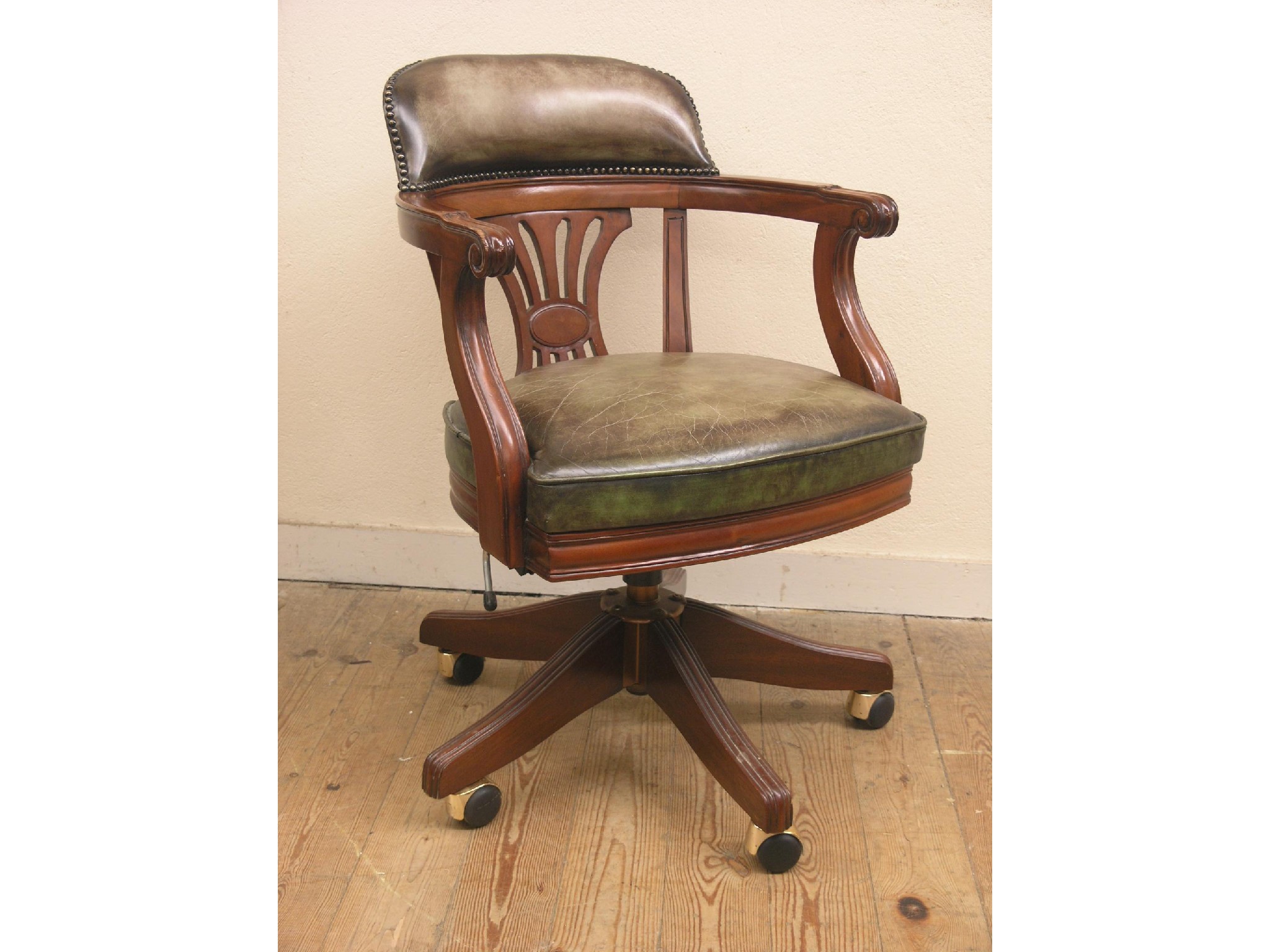 Appraisal: A mahogany revolving office chair upholstered in a green leather