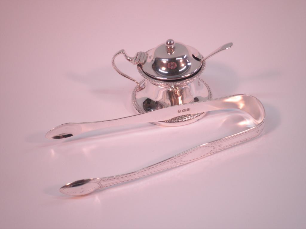 Appraisal: A silver circular mustard pot and associated spoon with a