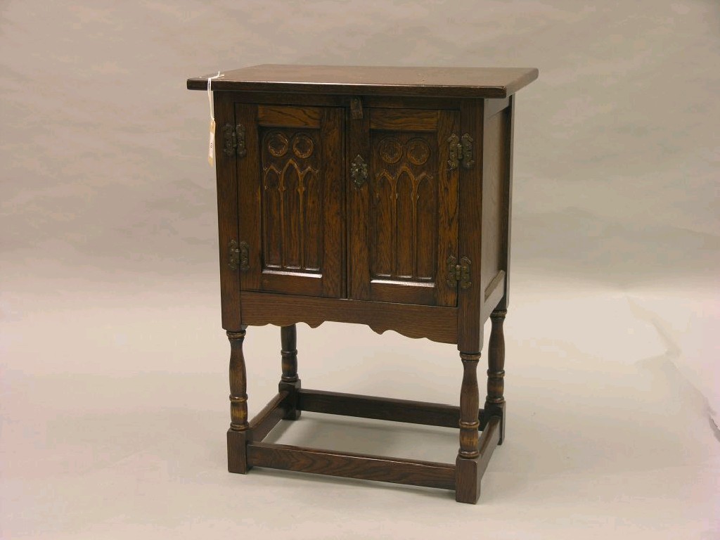 Appraisal: A reproduction dark oak bedside cupboard enclosed by a pair