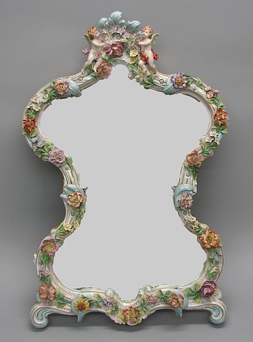 Appraisal: Cartouche form with applied colorful flowers floral cresting with putti