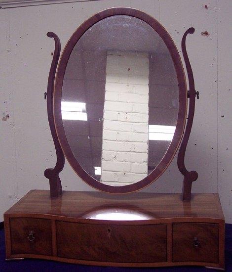 Appraisal: A mahogany oval swing frame toilet mirror with S-shaped supports