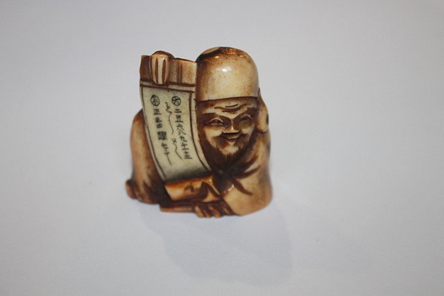 Appraisal: A JAPANESE BONE NETSUKE showing a seated Jurojin with open