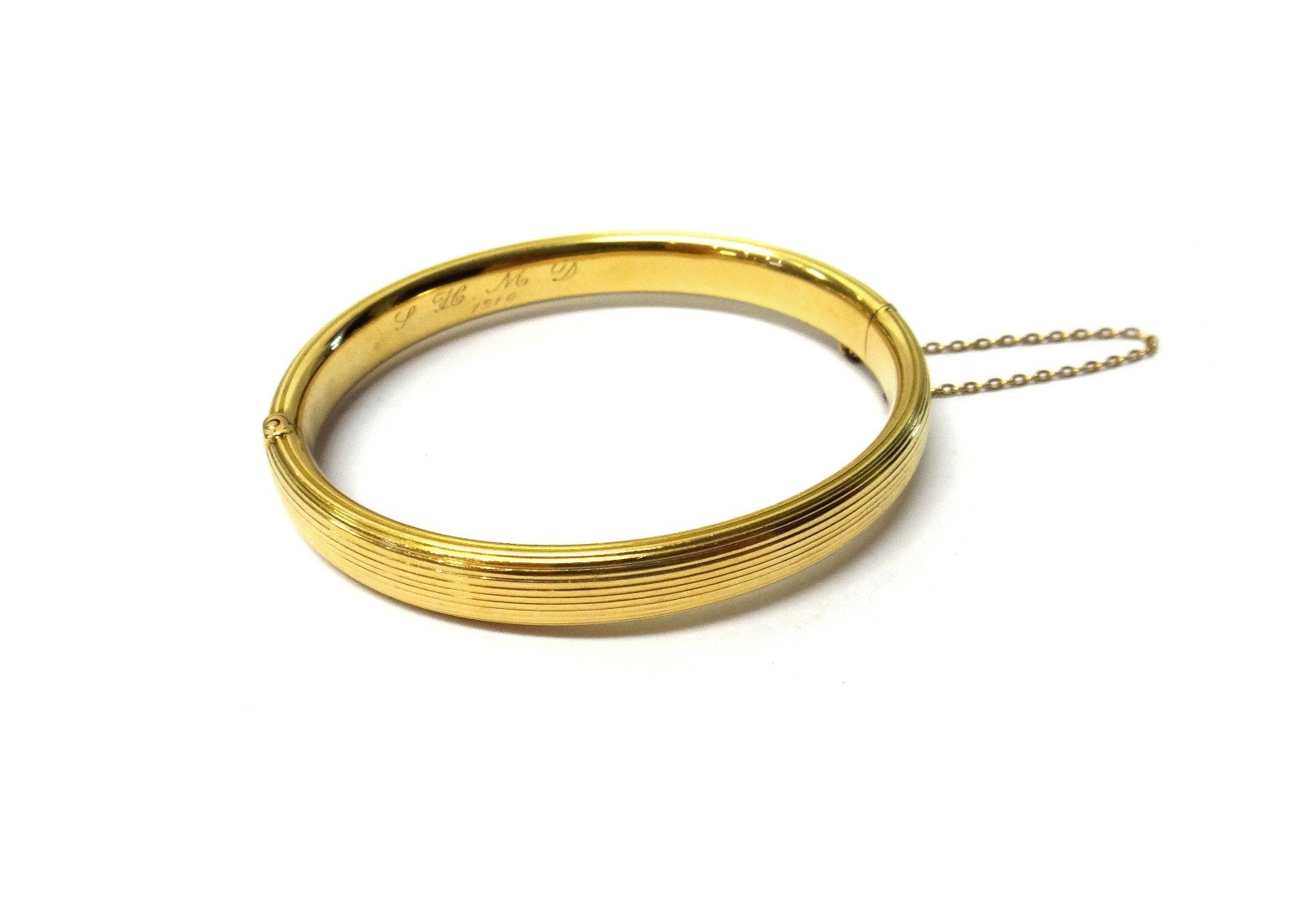 Appraisal: A gold oval hinged bangle with reeded decoration initial engraved