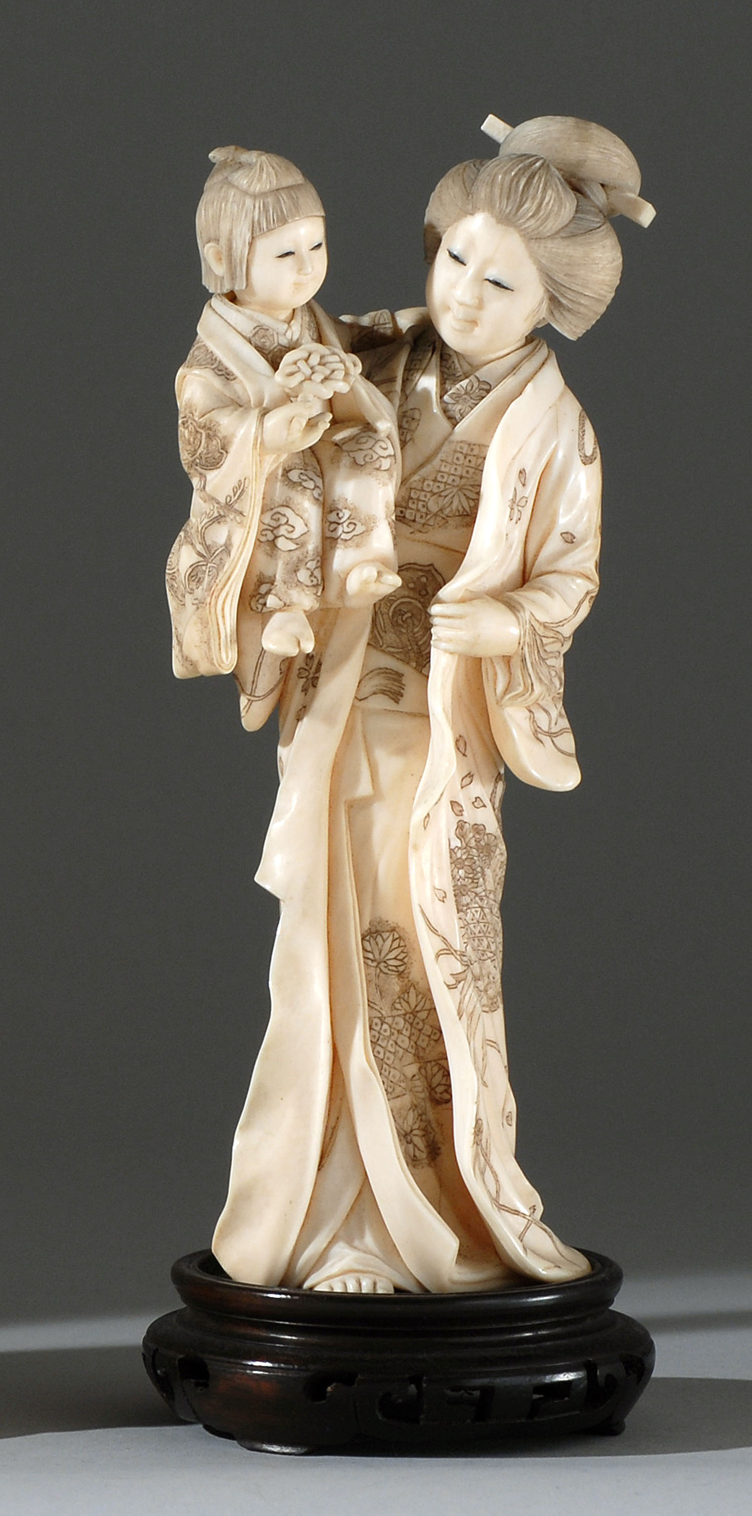 Appraisal: CARVED IVORY FIGURE GROUP Meiji PeriodDepicting a woman holding a