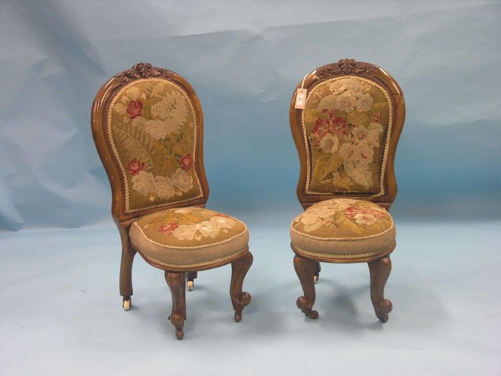 Appraisal: A pair of Victorian walnut nursing chairs carved crestings above