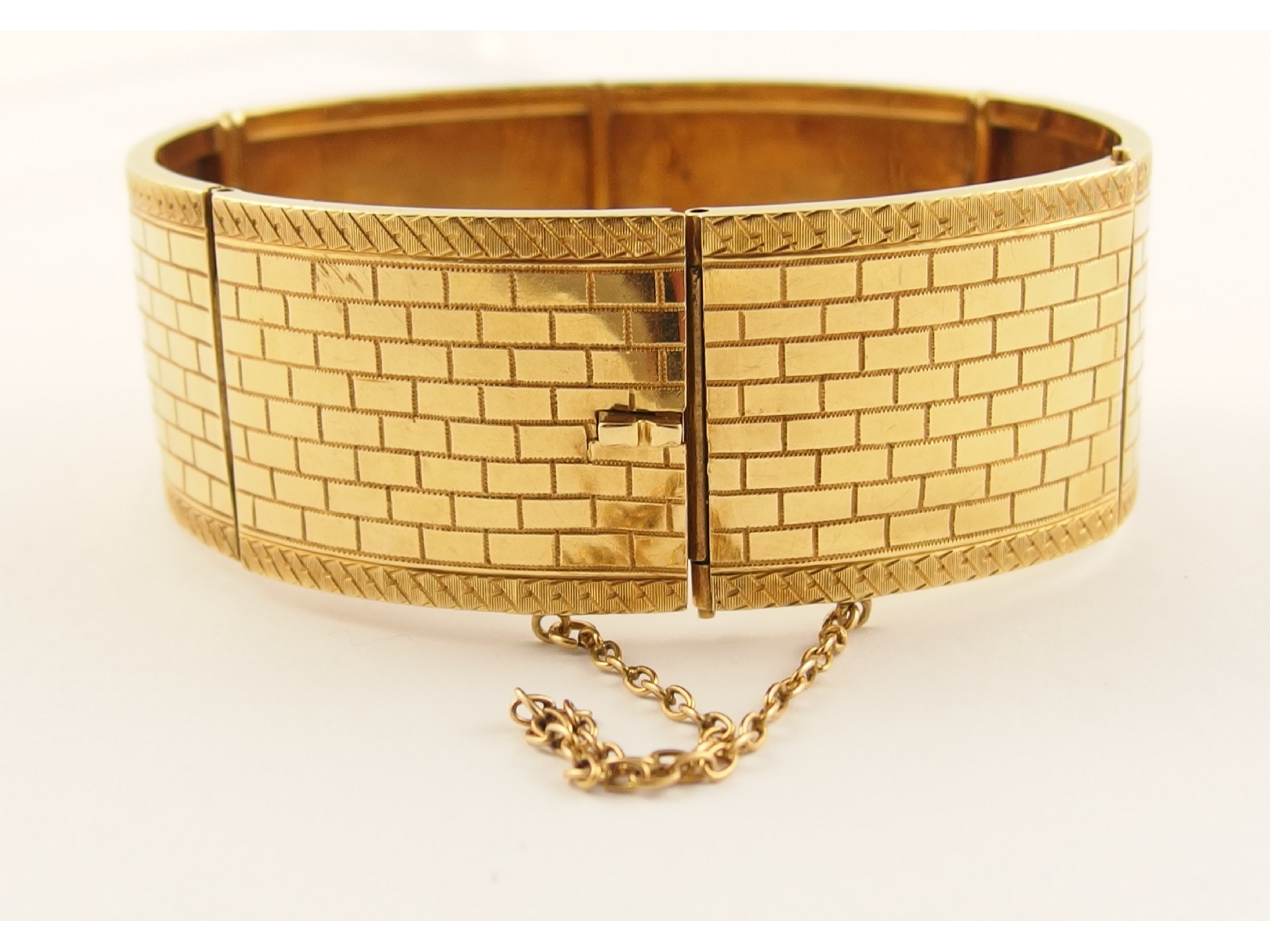 Appraisal: A French ct gold banglethe surface textured with an engraved