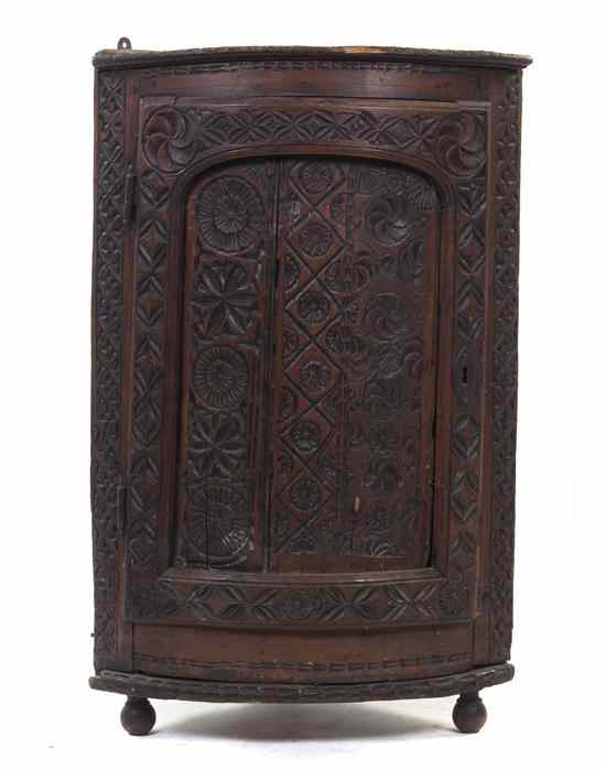 Appraisal: A Continental Carved Hanging Corner Cabinet of quarter-round form with