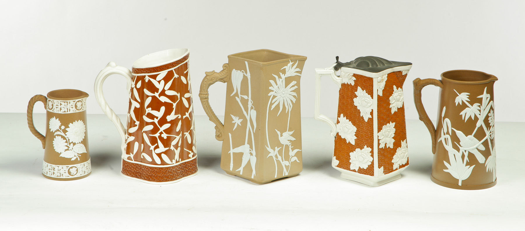 Appraisal: FIVE RELIEF MOLDED SCENIC BROWN AND WHITE PITCHERS English rd